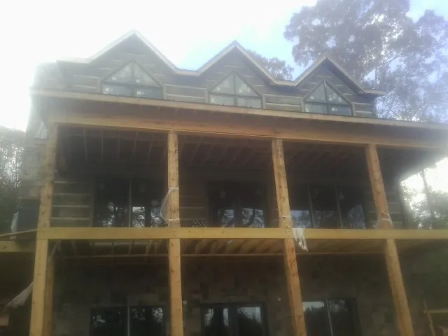 Dormers and porch framing on a large log home under construction — Roof Coating work by our crew in Julian